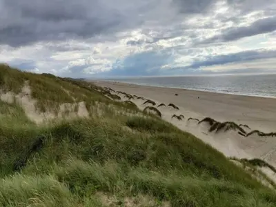 a sandy beach with people walking on the beach at 5 star holiday home in Løkken in Løkken