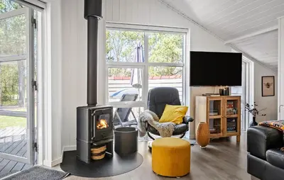 a living room with a fireplace and a chair and a television at Stunning Home In Hurup Thy With Sauna in Sønder Ydby