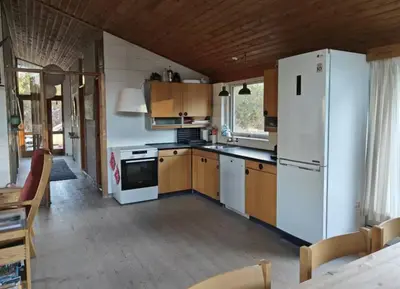 a kitchen with a white refrigerator and wooden cabinets at Dune House Near Bulbjerg in Frøstrup