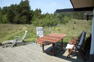 a wooden table and chairs sitting on a deck at Dune House Near Bulbjerg in Frøstrup
