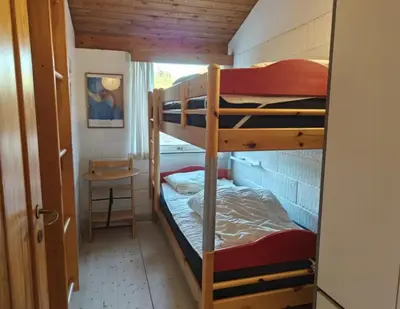a bunk bed room with two bunk beds and a table at Dune House Near Bulbjerg in Frøstrup