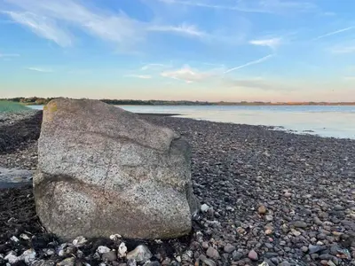 a large rock sitting on a rocky beach at Cozy Holiday Home With Forest And Fjord Views in Roslev