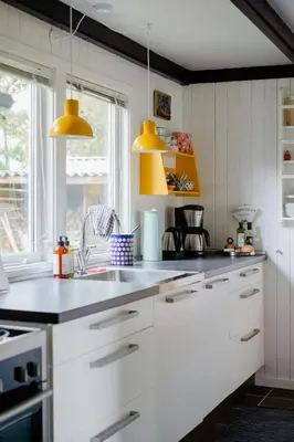 a kitchen with white cabinets and yellow pendant lights at Cozy Holiday Home With Forest And Fjord Views in Roslev