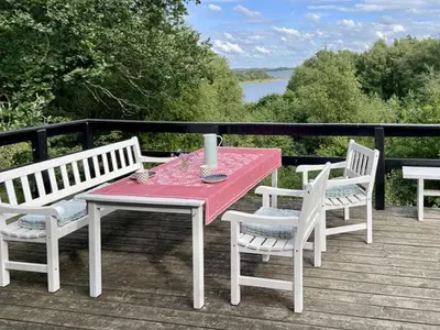 a picnic table with two chairs and a red table and chairs at Cozy Holiday Home With Forest And Fjord Views in Roslev
