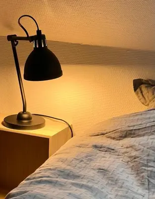 a lamp sitting on a table next to a bed at Bright Nordic Loft Apartment in Spottrup