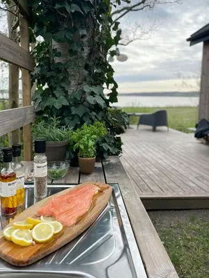 a fish on a cutting board on a table with lemon slices at Modern Wooden House Near Halkær Bredning in Nibe