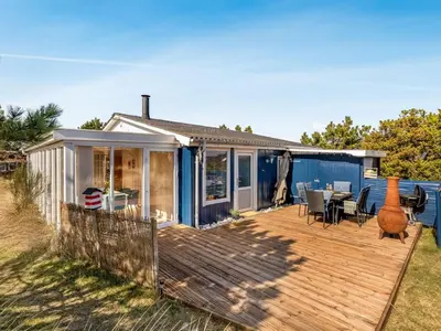 a small blue house with a deck with a table and chairs at Holiday Home Mynthe - 500m from the sea by Interhome in Thisted