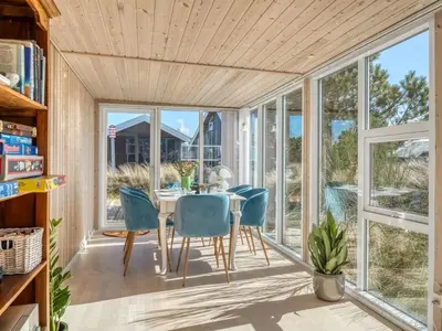 a dining room with a table and chairs and large windows at Holiday Home Mynthe - 500m from the sea by Interhome in Thisted