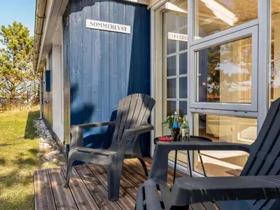 a rocking chair and a table on a porch at Holiday Home Mynthe - 500m from the sea by Interhome in Thisted
