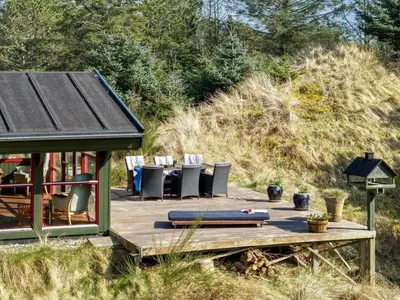 a house with a deck with chairs and a table at Holiday Home Nimrod - 800m from the sea by Interhome in Blokhus