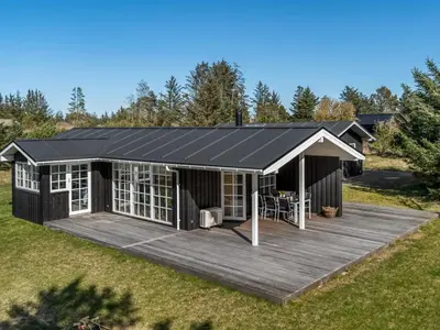 a large black house with a wooden deck at Holiday Home Jork - 1km from the sea by Interhome in Saltum