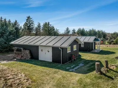 a black shed with a white door in a yard at Holiday Home Jork - 1km from the sea by Interhome in Saltum
