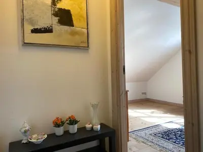 a room with a table with flowers and a painting on the wall at Dejlig gårdhave 5 soveværelser in Harboør