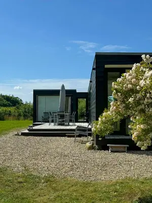 a black house with a table and chairs in front of it at Modern Holiday Home By Limfjord in Øster Assels