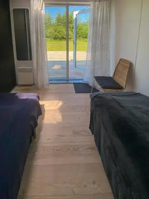 a room with two beds and a tv and a chair at Modern Holiday Home By Limfjord in Øster Assels