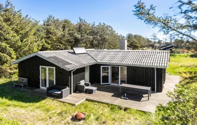 a small black cabin with a deck and chairs at 3 Bedroom Pet Friendly Home In Løkken in Løkken