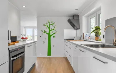 a white kitchen with a green tree decal on the wall at 3 Bedroom Pet Friendly Home In Løkken in Løkken