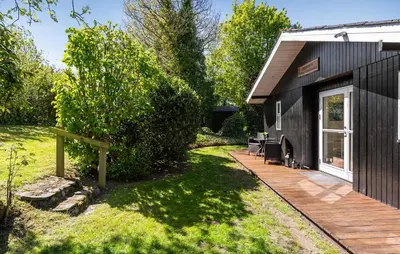 a black house with a deck and a yard at 3 Bedroom Nice Home In Farsø in Farsø