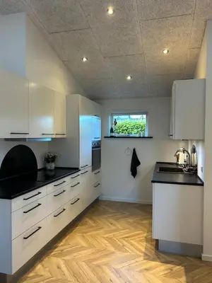a kitchen with white cabinets and black counter tops at Nyrenoveret,hyggeligt og centralt hus in Holstebro