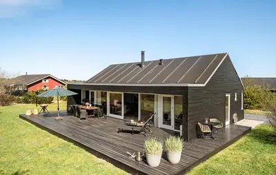 a black house with a deck in a yard at Gorgeous Home In Brovst With Sauna in Brovst