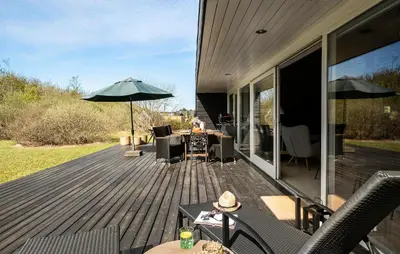 a wooden deck with a table and an umbrella at Gorgeous Home In Brovst With Sauna in Brovst