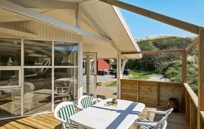 a patio with a table and chairs on a deck at 3 Bedroom Beautiful Home In Blokhus in Blokhus