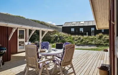 a patio with a table and chairs on a deck at 3 Bedroom Beautiful Home In Blokhus in Blokhus
