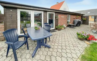 a patio with a table and chairs and a house at Cozy Home In Thyborøn With Wifi in Thyborøn