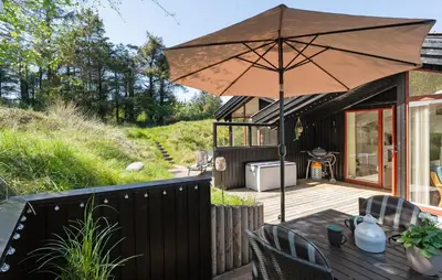 a patio with a table and an umbrella at 3 Bedroom Beautiful Home In Blokhus in Blokhus
