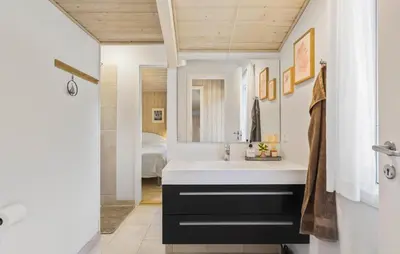 a bathroom with a sink and a mirror and a bed at 3 Bedroom Beautiful Home In Blokhus in Blokhus