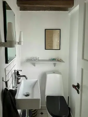 a bathroom with a black toilet and a sink at Charmerende Villa Havly Nær Vesterhavet in Harboør