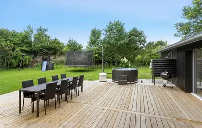 a wooden deck with a grill and a table and chairs at 3 Bedroom Stunning Home In Spøttrup in Spottrup