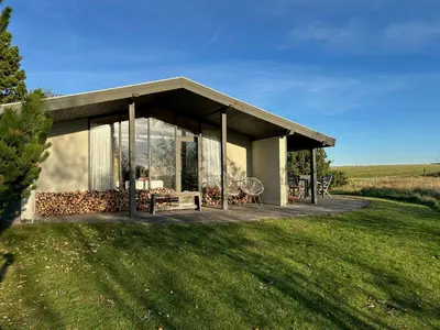a small house with a deck in the middle of a field at Summer House With Fields And Fjord Views in Thyholm