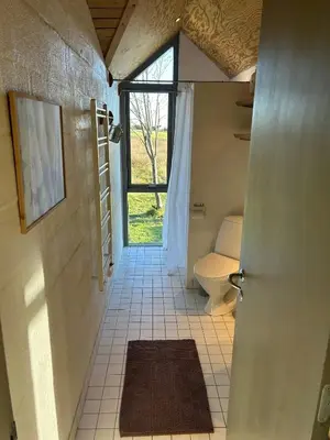 a bathroom with a toilet and a door with a window at Summer House With Fields And Fjord Views in Thyholm