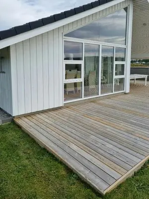 a deck with glass doors on a house at Modern House Close To The North Sea in Tranum