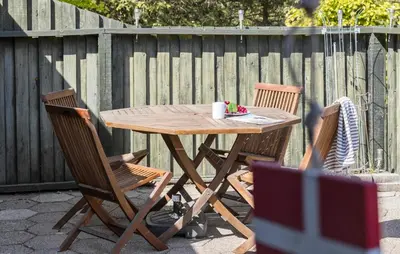 a wooden table and chairs in a backyard with a fence at 3 Bedroom Stunning Home In Blokhus in Blokhus