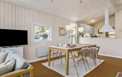 a dining room with a table and a couch at 3 Bedroom Stunning Home In Blokhus in Blokhus