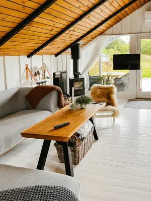 a living room with a table and a fireplace at Simple Cottage Close To Limfjorden in Åbybro