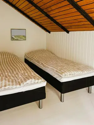 two beds in a room with wooden ceilings at Simple Cottage Close To Limfjorden in Åbybro
