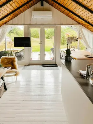 a living room with a white floor and glass doors at Simple Cottage Close To Limfjorden in Åbybro