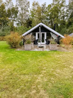 a small house with a grass field in front of it at Simple Cottage Close To Limfjorden in Åbybro