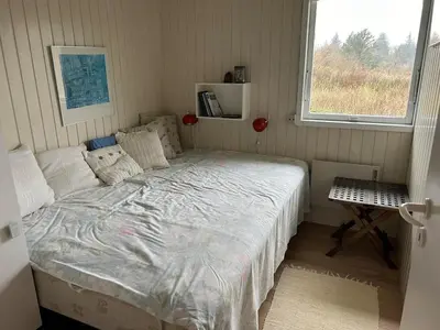 a small bedroom with a bed and a window at Hygge in the North Sea Cabin in Fjerritslev
