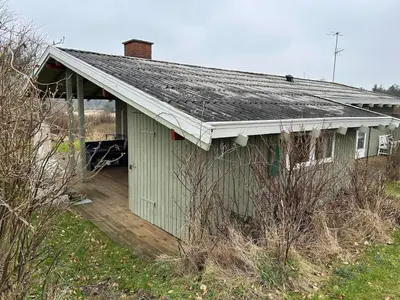 a green building with a roof on a field at Hygge in the North Sea Cabin in Fjerritslev