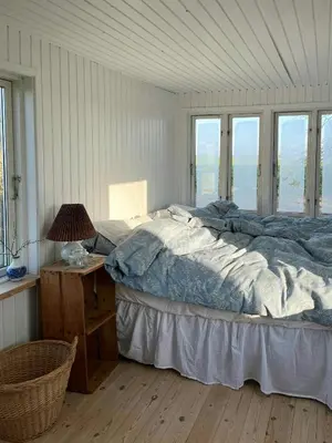 a bedroom with a bed and a table and windows at Cozy Wagon House With Views Over The Limfjord in Roslev