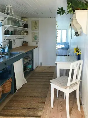 a kitchen with a white table and a white chair at Cozy Wagon House With Views Over The Limfjord in Roslev