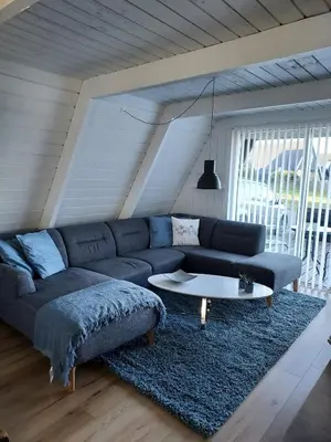 a living room with a blue couch and a table at Holiday home golf house in beautiful Himmerland Farsø in Farsø