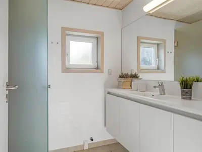 a white bathroom with two sinks and a mirror at Holiday Home Elni - 350m from the sea by Interhome in Blokhus