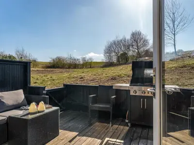 a patio with a grill and a couch on a deck at Apartment Kauno - 16km to the fjord by Interhome in Farsø