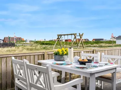 a white table with chairs and flowers on a deck at Holiday Home Arkil - 200m from the sea by Interhome in Harboør