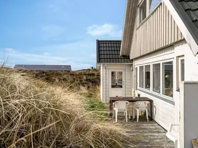 a small white house with a table and chairs on a porch at Holiday Home Wighlek - 800m from the sea by Interhome in Snedsted